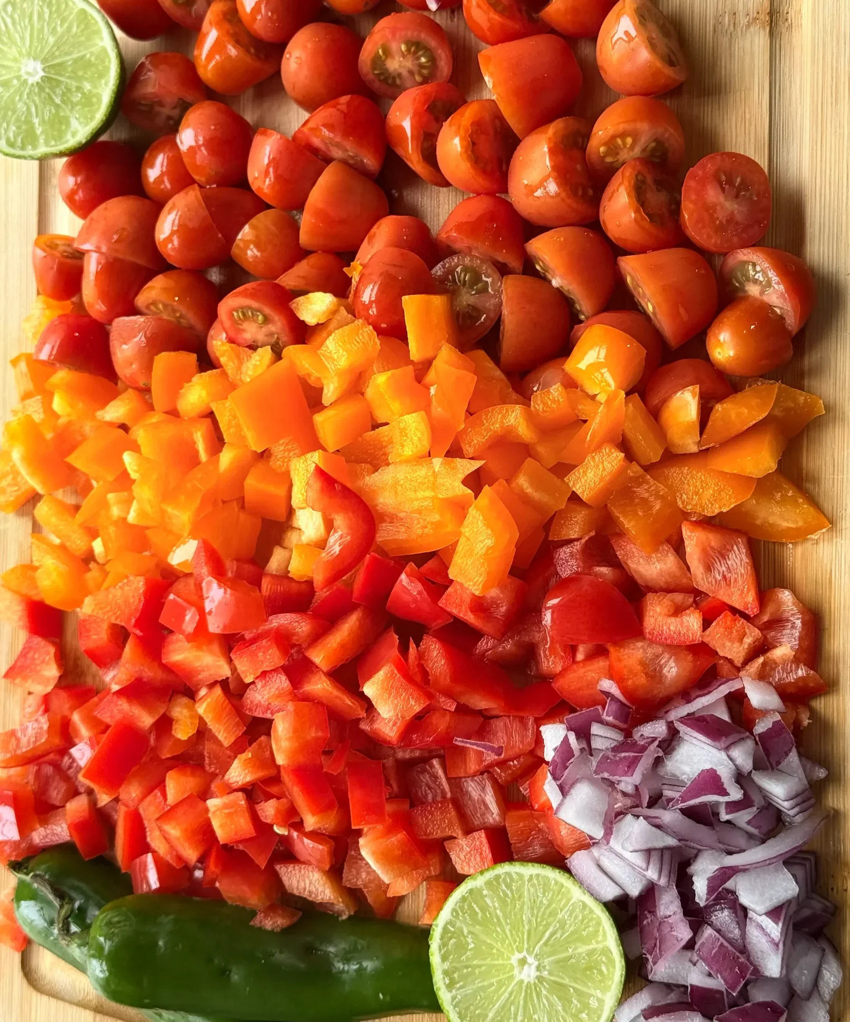Assortment of chopped vegetables aligned on a wooden cutting board.