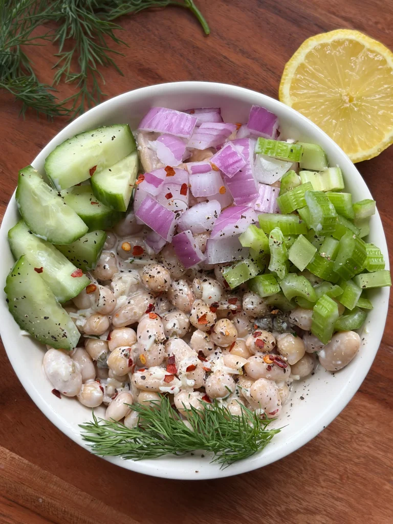Caesar chickpea salad with sliced cucumbers, red onions, and celery diced. Sprinkled fresh dill on top.