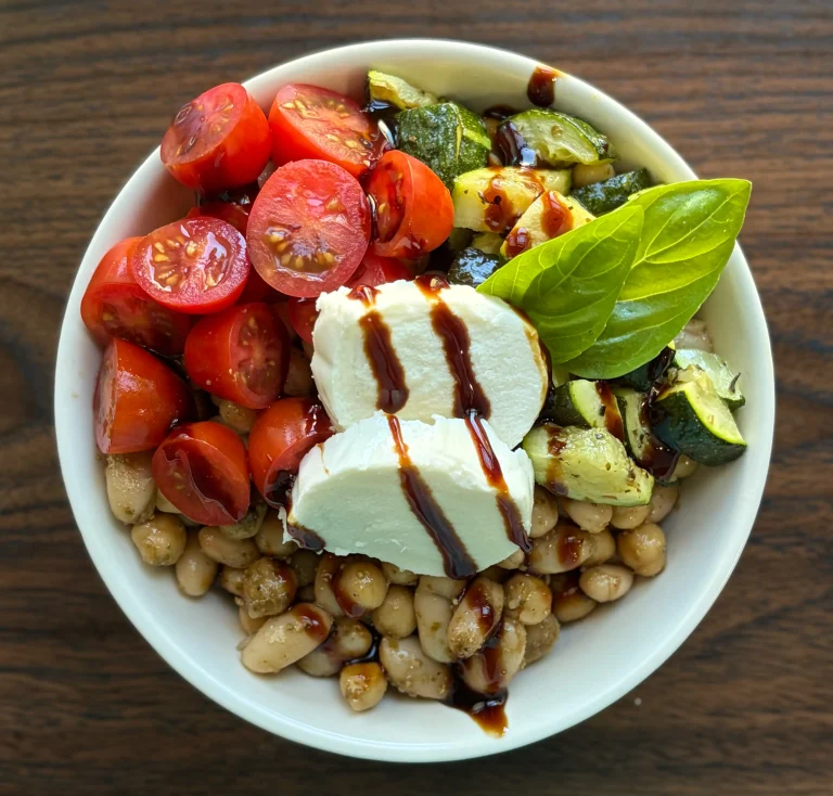 Caprese bean salad topped with cherry tomatoes, baked zucchini, fresh mozzarella and basil with a balsamic glaze drizzled on top.