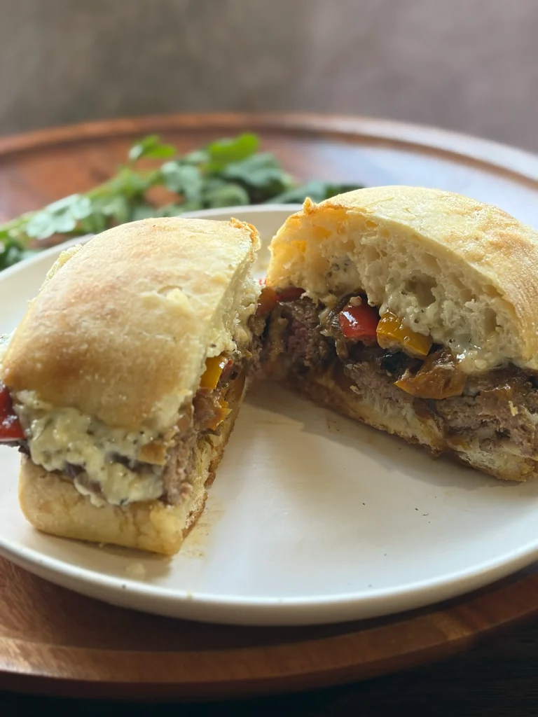 Steak sandwiches on a white plate showing the steak and ciabatta bread with a creamy spread. 