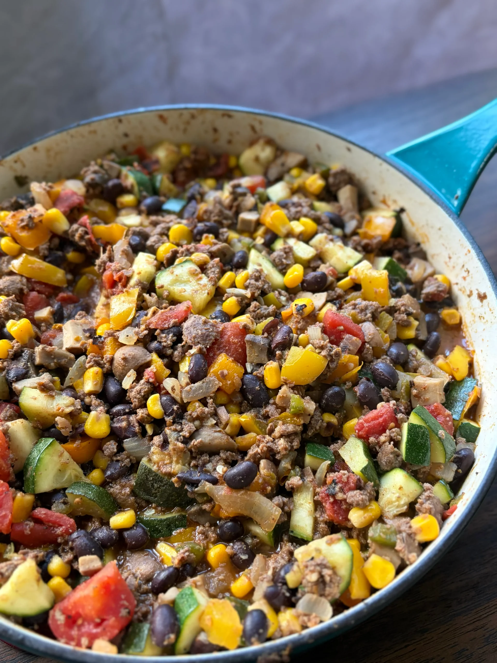 Ground beef, tomatoes, bell peppers, and zucchini all mixed together in a skillet with seasonings.