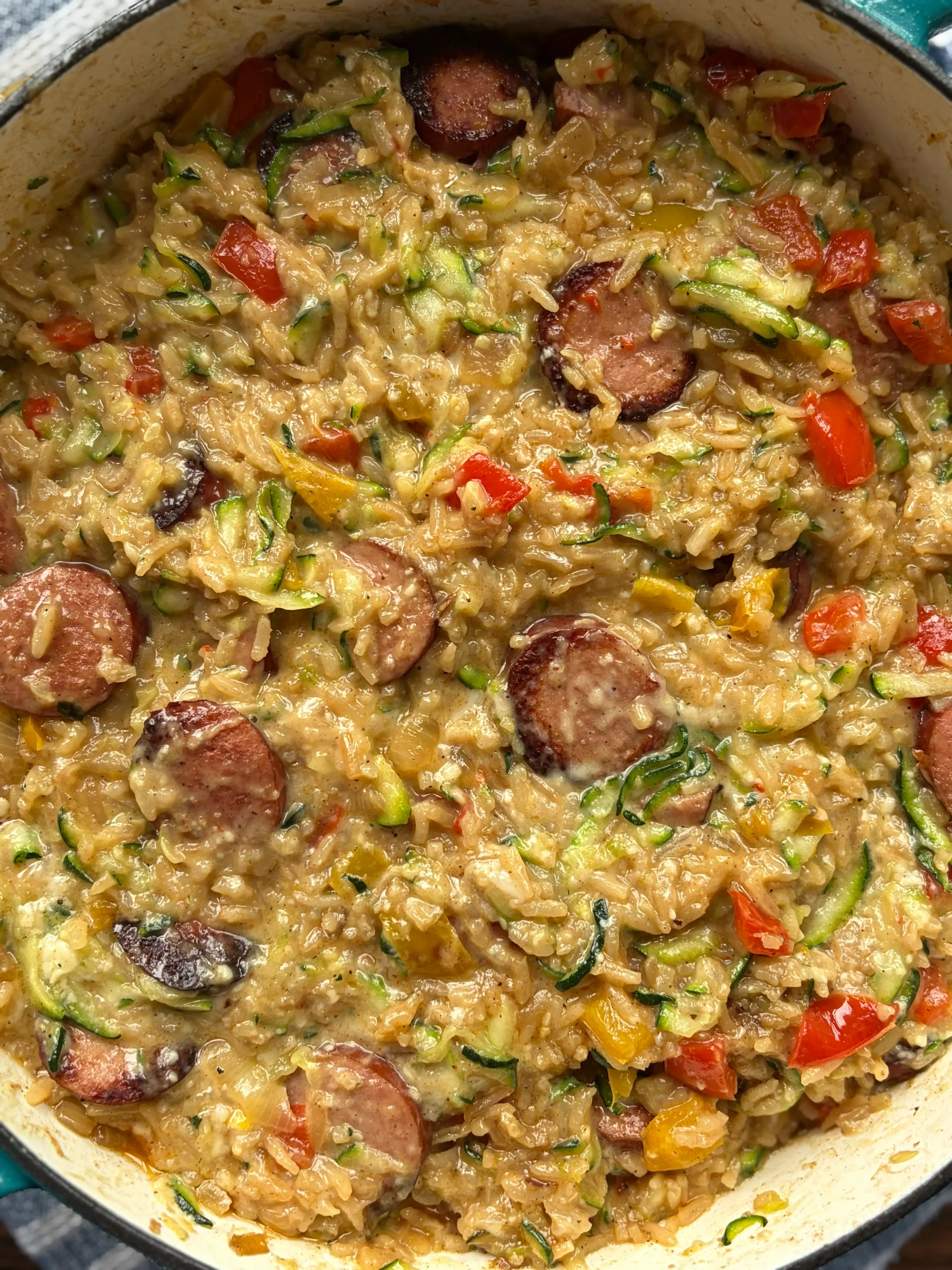 Sausage rice and zucchini in a skillet. Cooking with cheese and bell peppers.