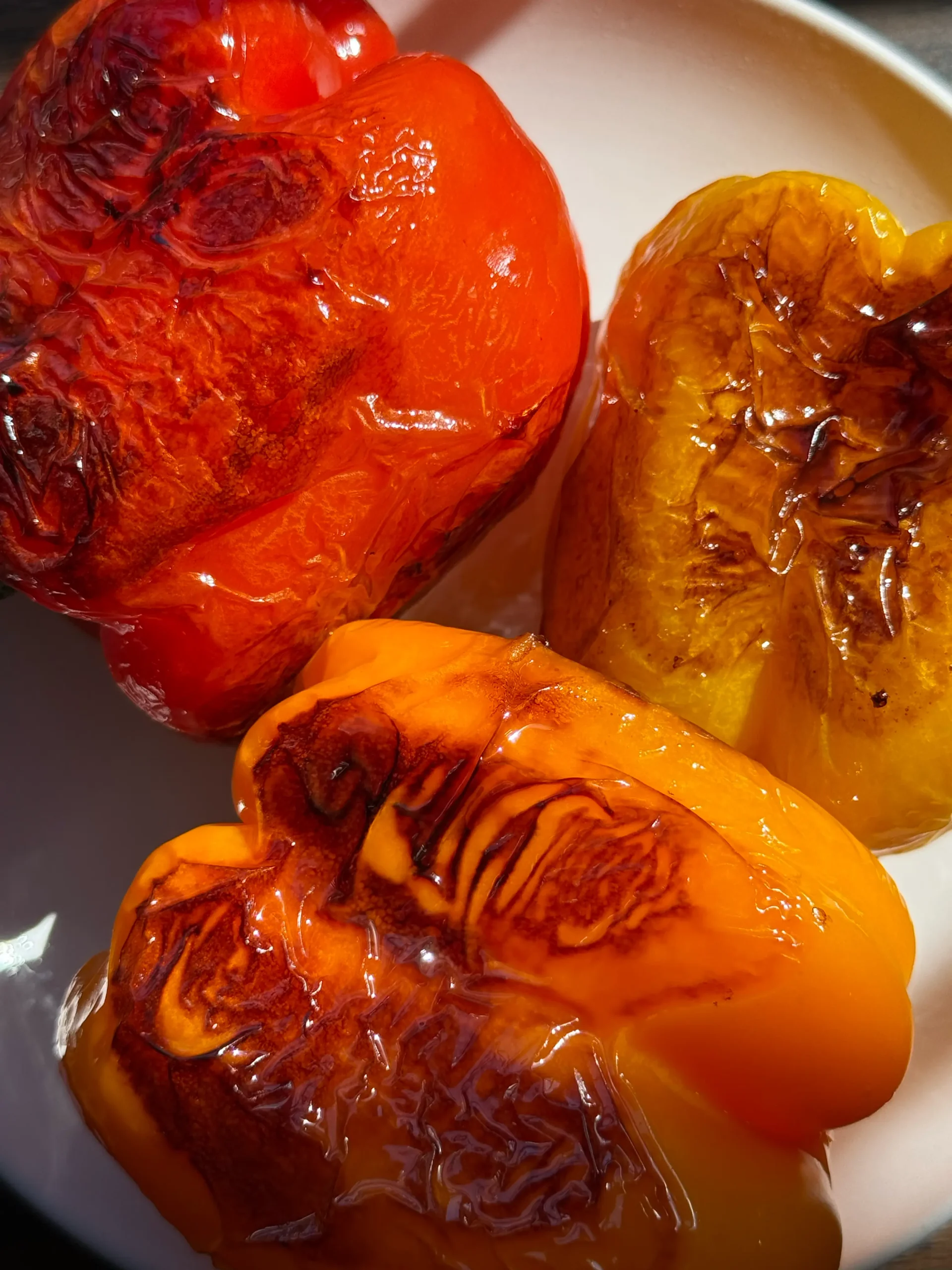 Roasted peppers with skin on, one red, one yellow and one orange.