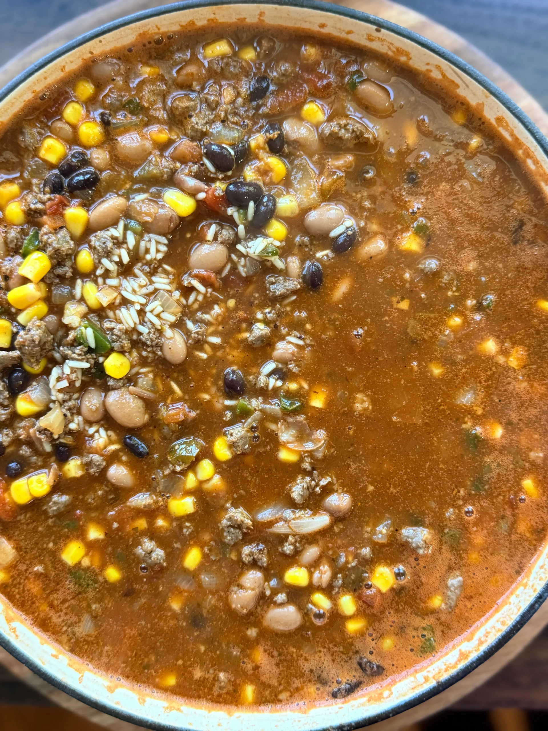 Skillet with ground beef, beans, rice and corn before cooking.