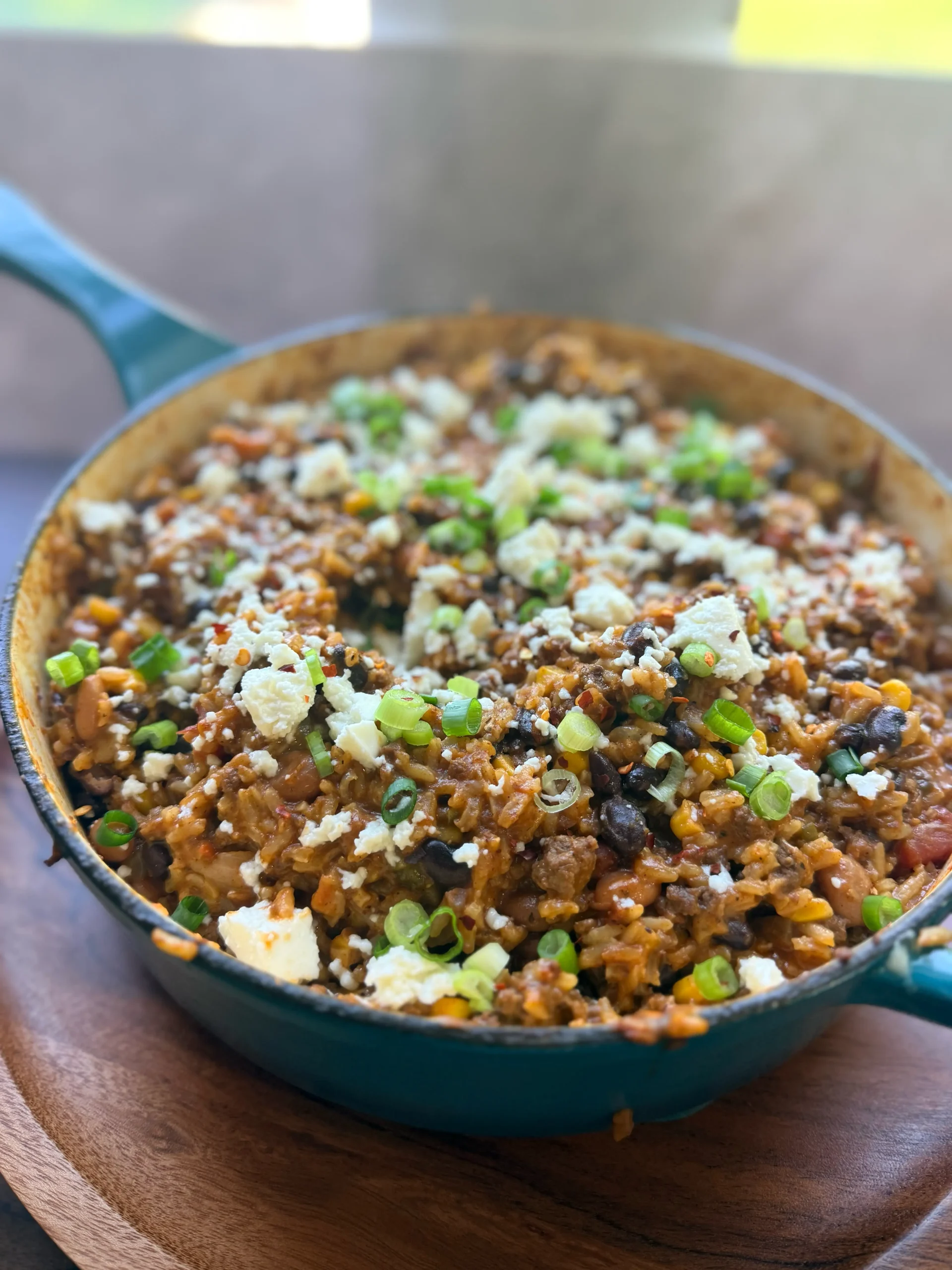 Blue skillet with taco bean and rice cooked with cheese on top.