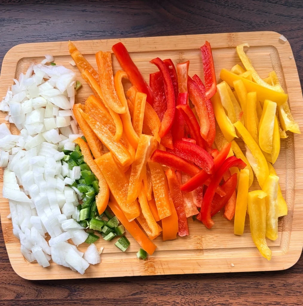 Diced onion, diced jalapenos, and diced bell peppers on a cutting board.