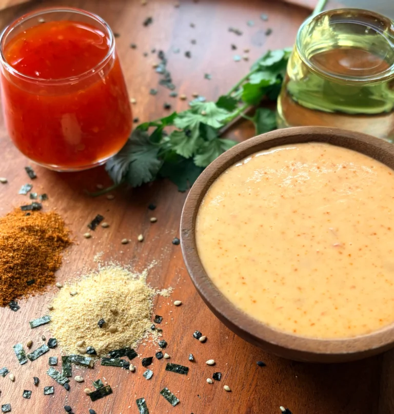 A bowl of yum yum sauce on the bottom right. There is a small bowl of chili sauce and rice vinegar with fresh cilantro for decor.