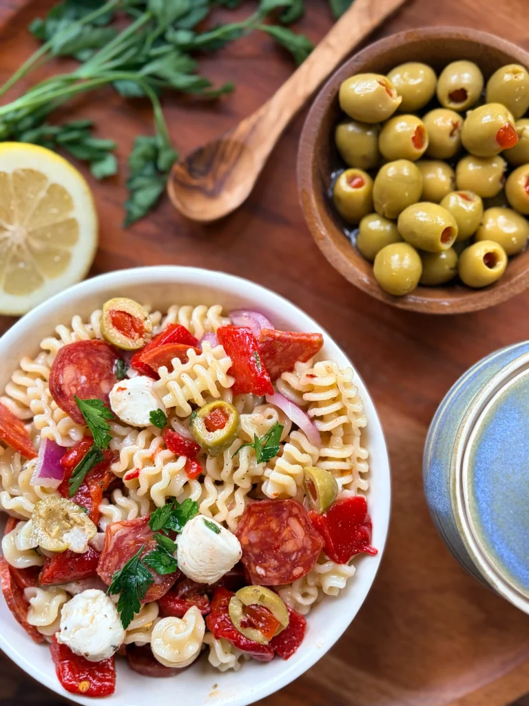 A bowl of muffuletta pasta salad with a bowl of olives on the side.