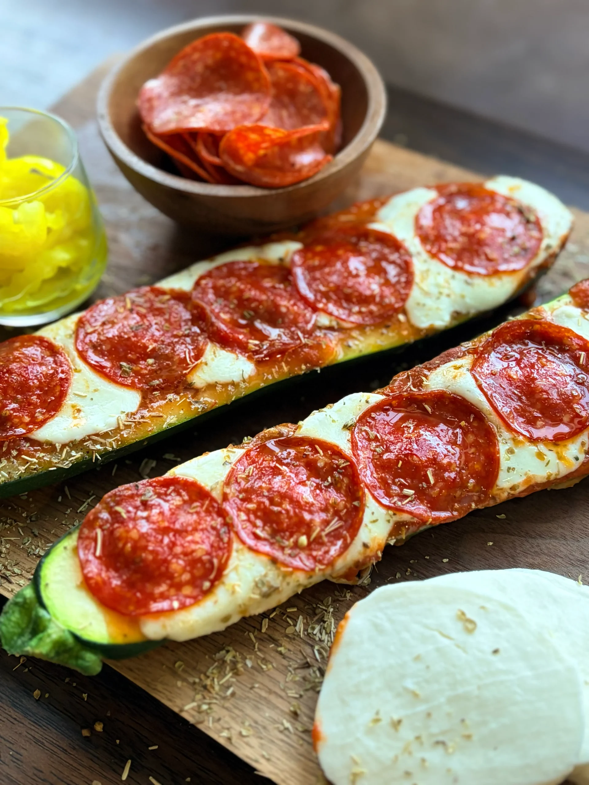 Two zucchini pizzas with mozzarella cheese and pepperoni on the side.