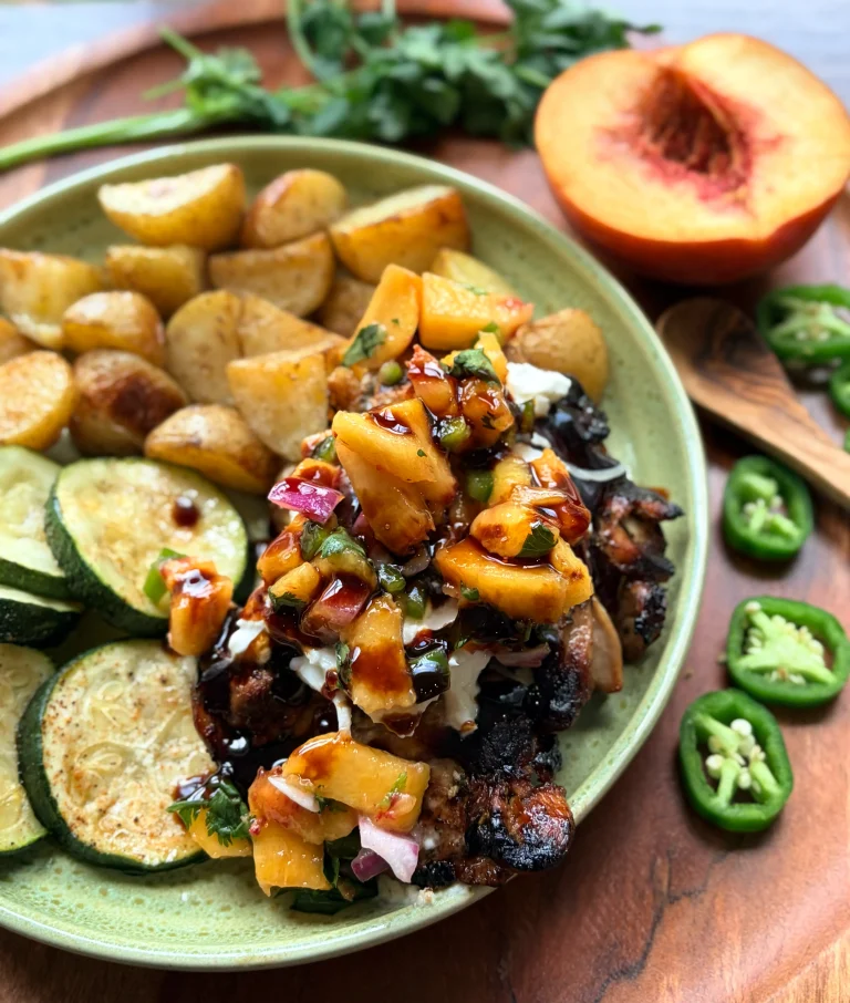 Balsamic glazed chicken with fresh peach salsa. Roasted potatoes and sliced zucchini on a green plate.