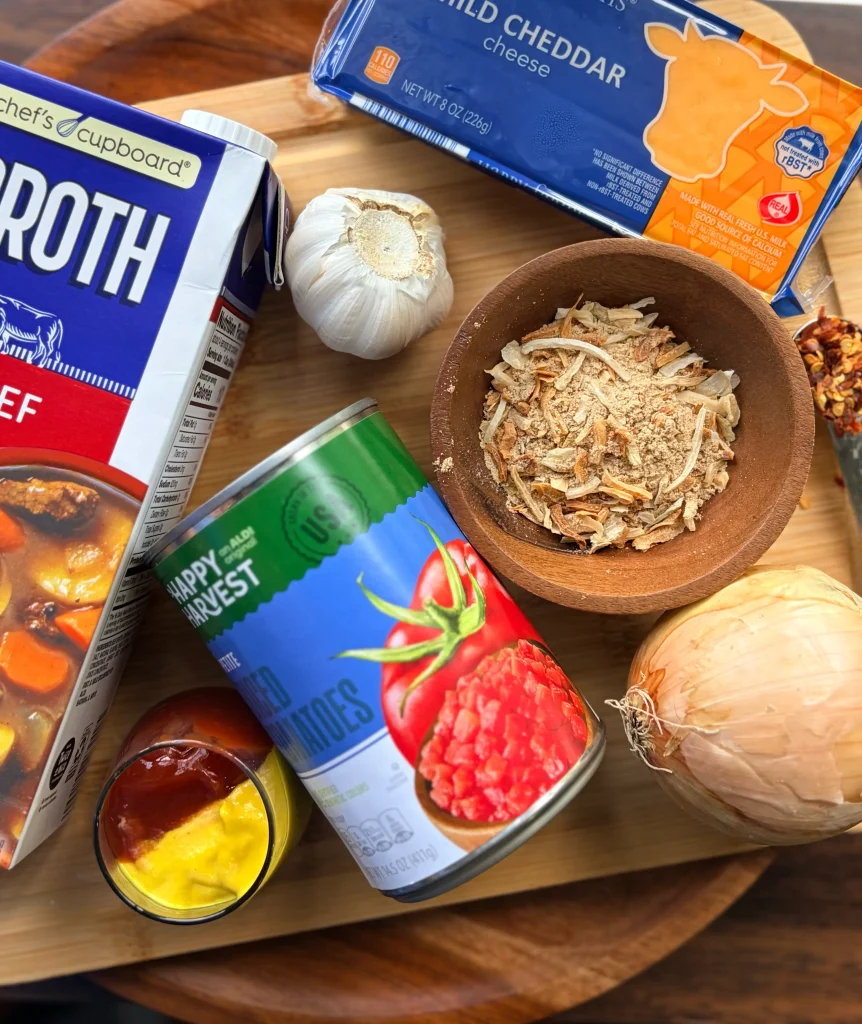 Beef broth with a can of tomatoes. A block of cheddar cheese and a white onion.