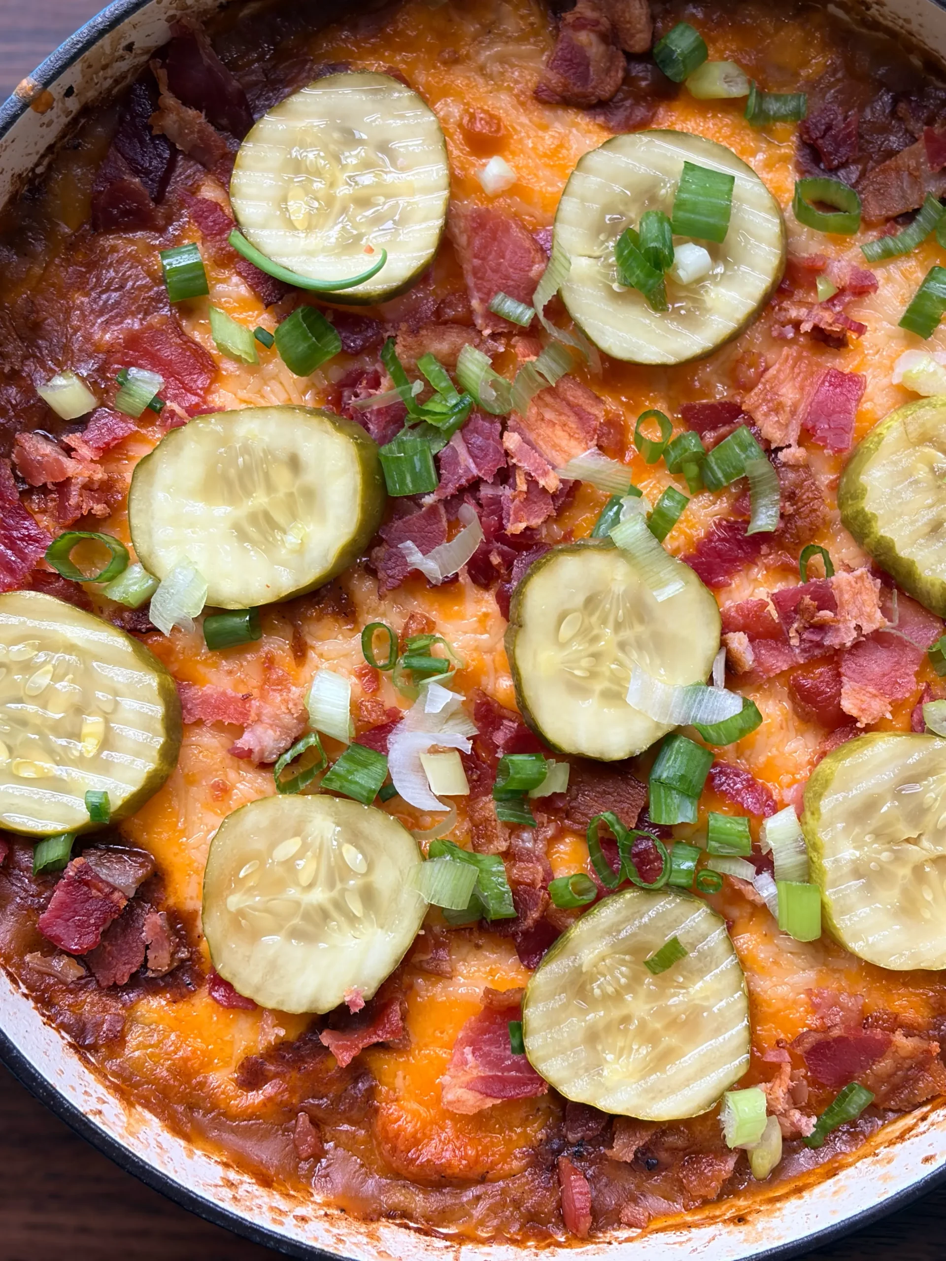 Cheeseburger Shepherd's pie topped with pickles and green onion in a skillet.