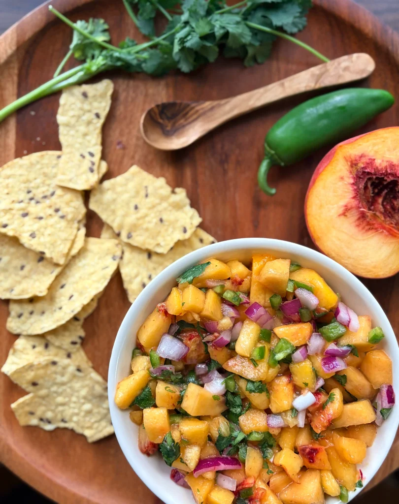 Fresh peach salsa with tortilla chips and a whole jalapeno.