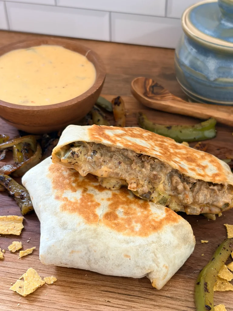 Philly cheesesteak crunchwrap with a bowl of cheese whiz on the side