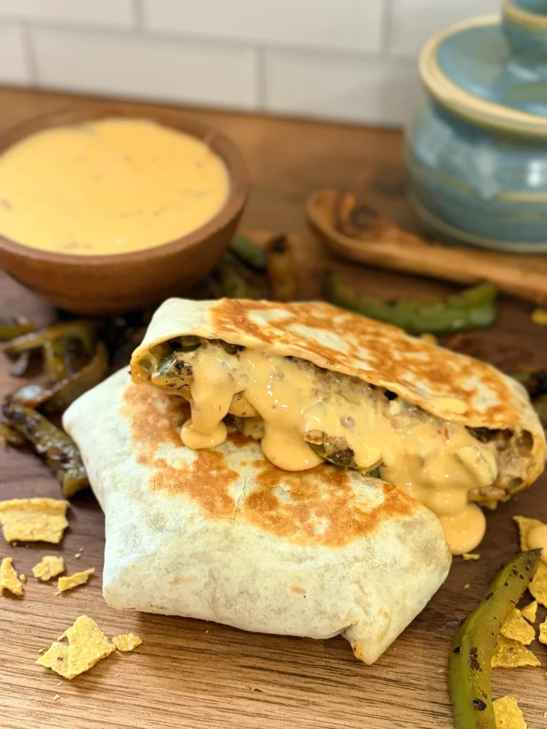 Philly cheesesteak crunchwrap with a bowl of cheese whiz on the side.