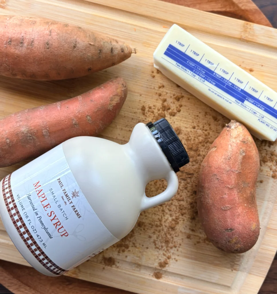 Sweet potatoes and a stick of butter with a jug of maple syrup.