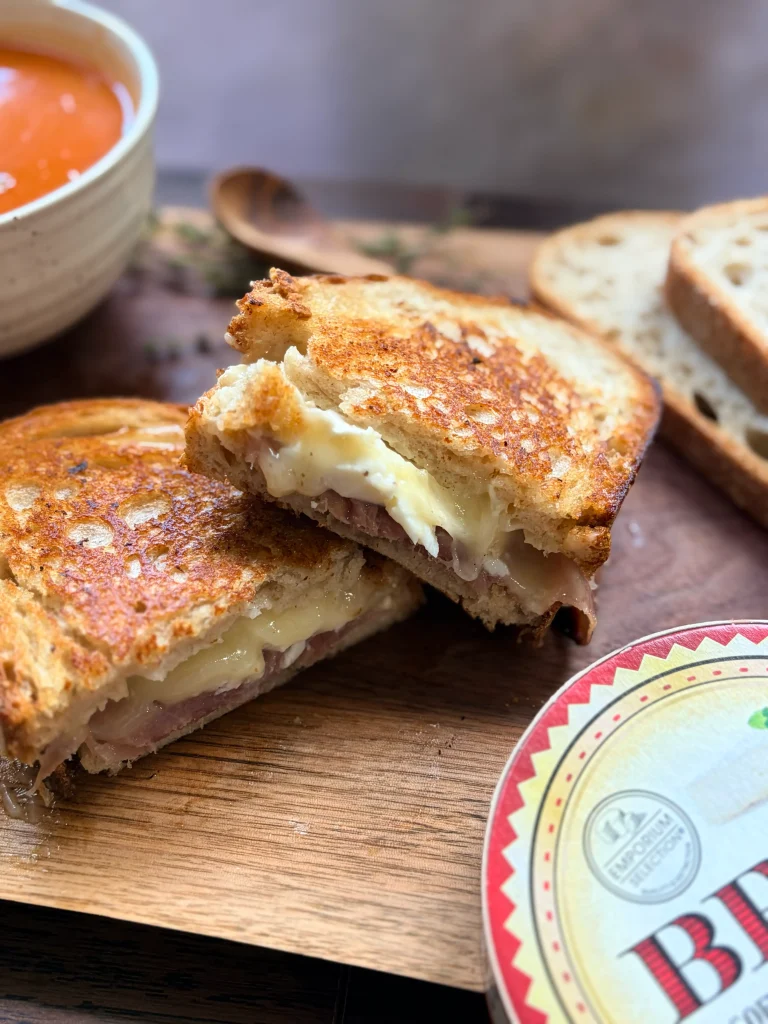 Hot honey brie and prosciutto grilled cheese sandwich with a bowl of tomato soup.