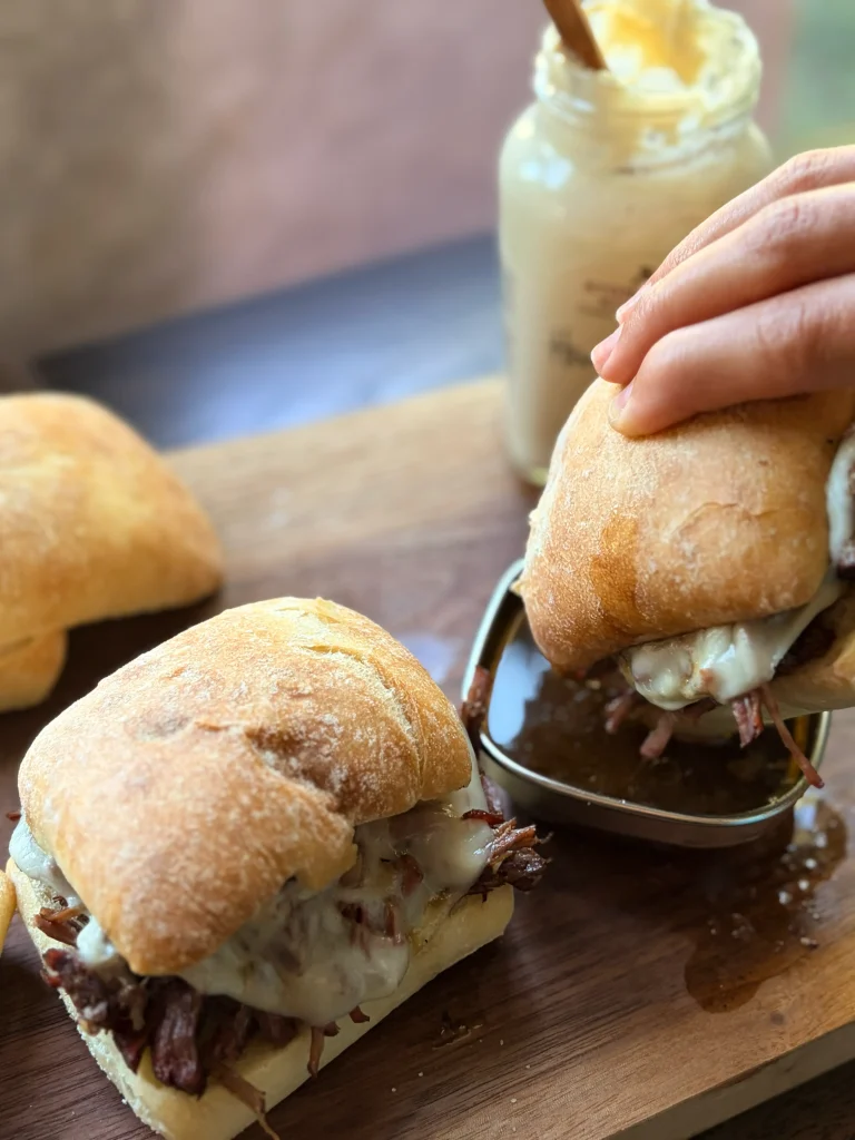 Holding a juicy french dip sandwich from the crockpot.