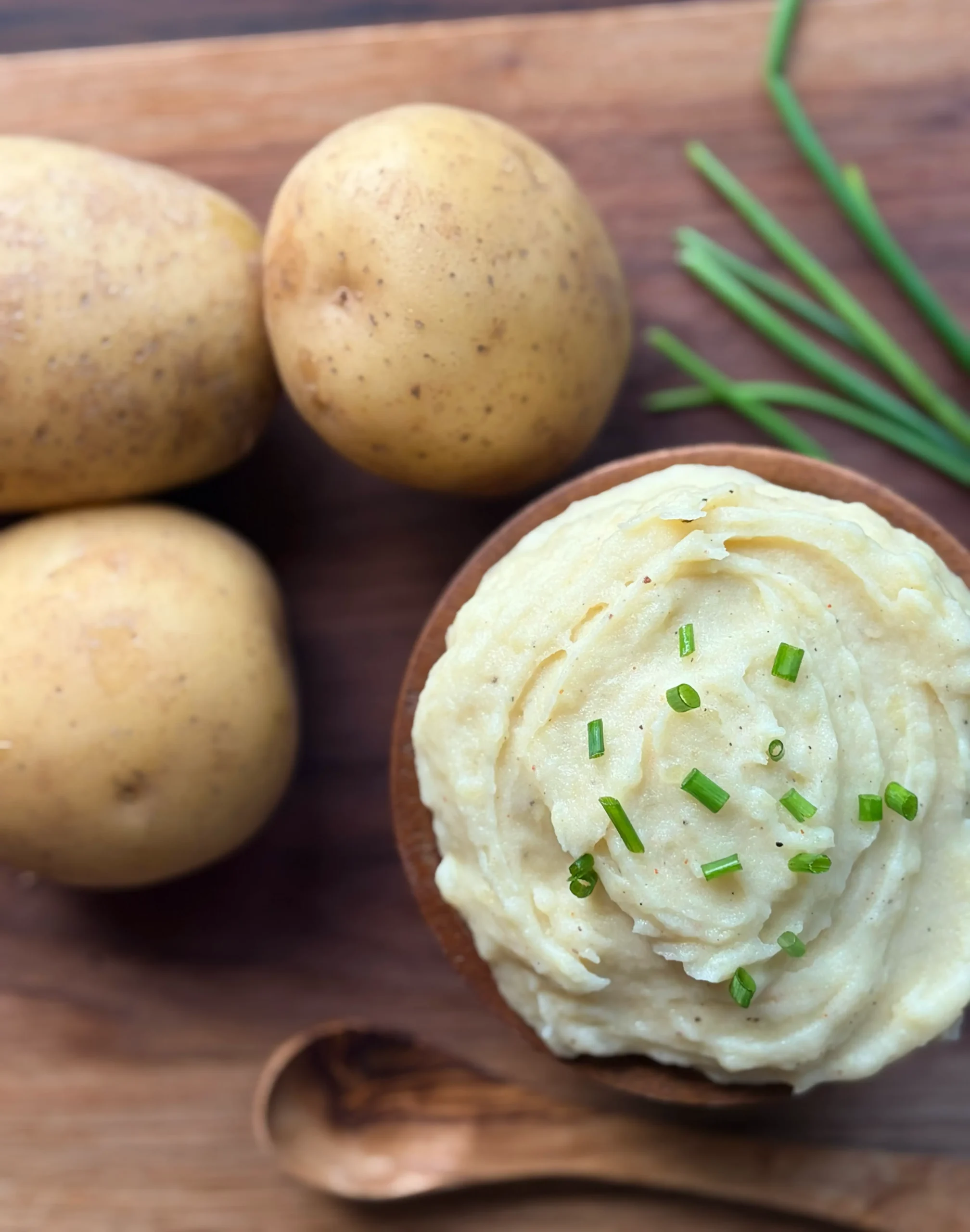 Yukon gold potatoes next to whipped mashed potatoes with chives for garnish