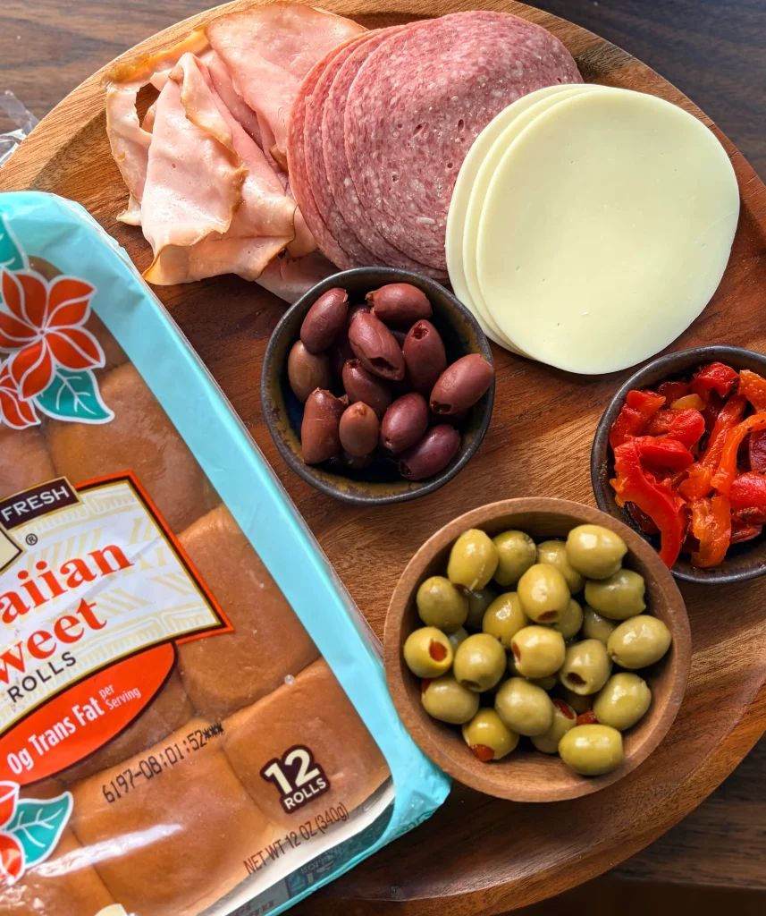 Package of hawaiian rolls with ingredients for mufuletta sliders.