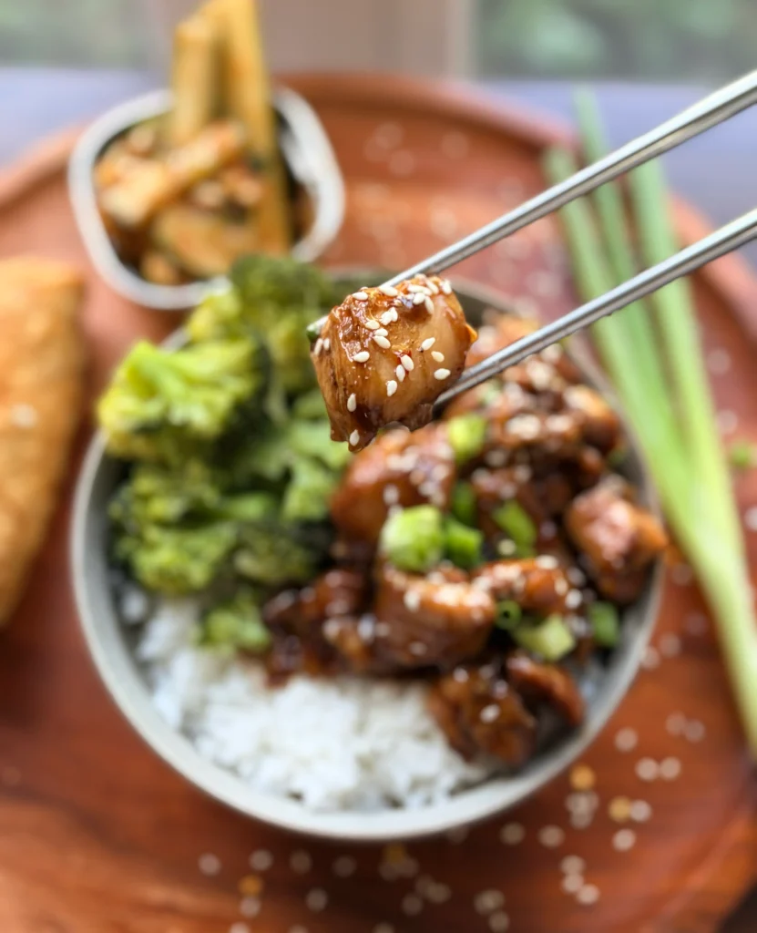 Honey-soy glazed chicken rice bowls with broccoli and an eggroll. Spicy cucumber salad on the side with a green onion sprig for garnish.